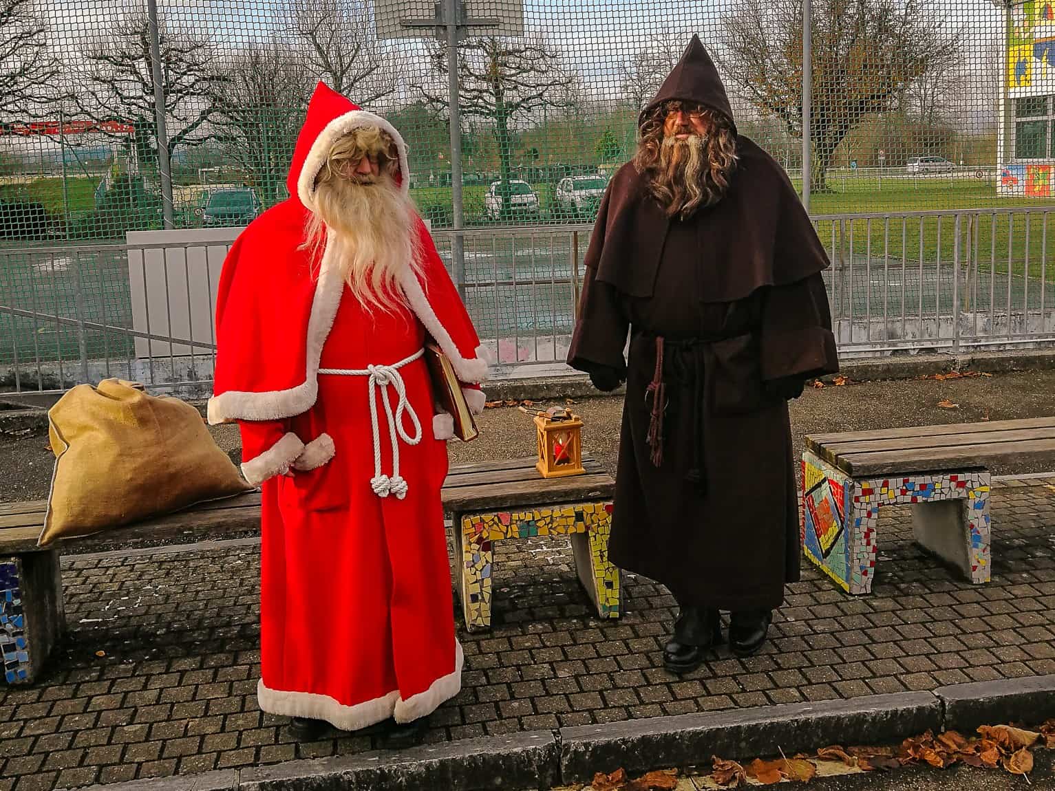 Two men dressed up in costumes of Swiss Santa Samichlaus and his helper Schmutzli